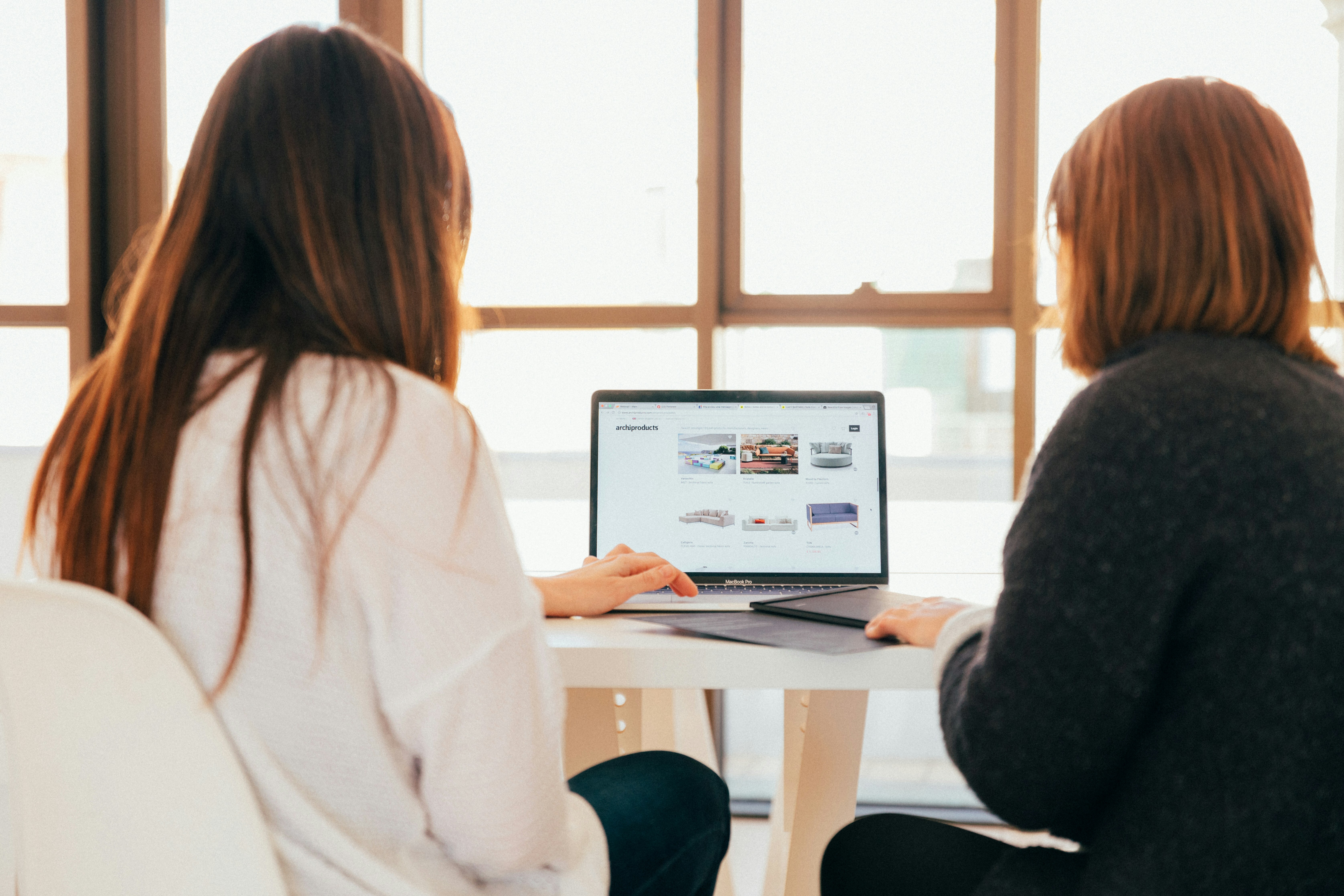 Two women sitting in front of a computer.