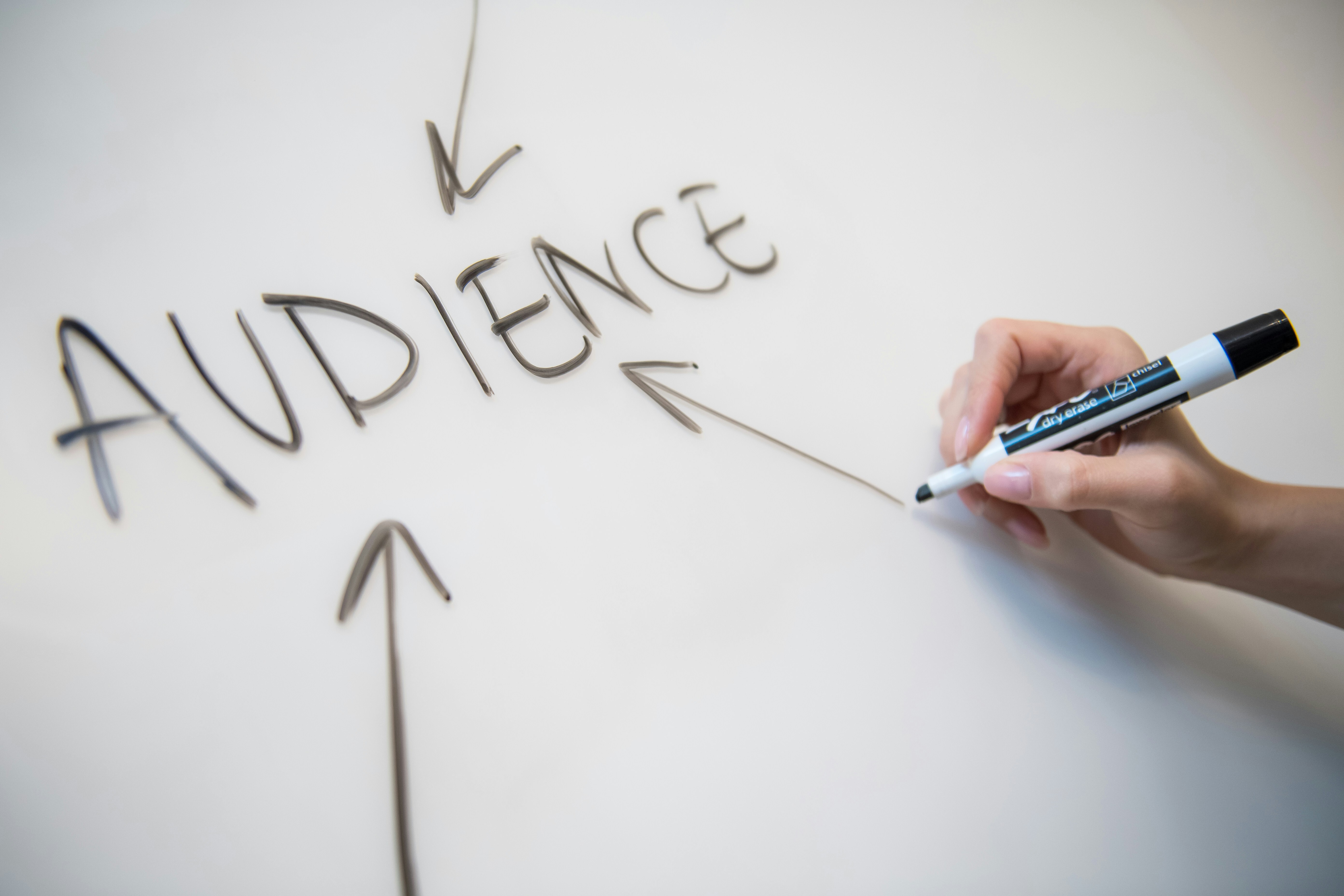 The word “audience” is written on a whiteboard with arrows pointing to it.