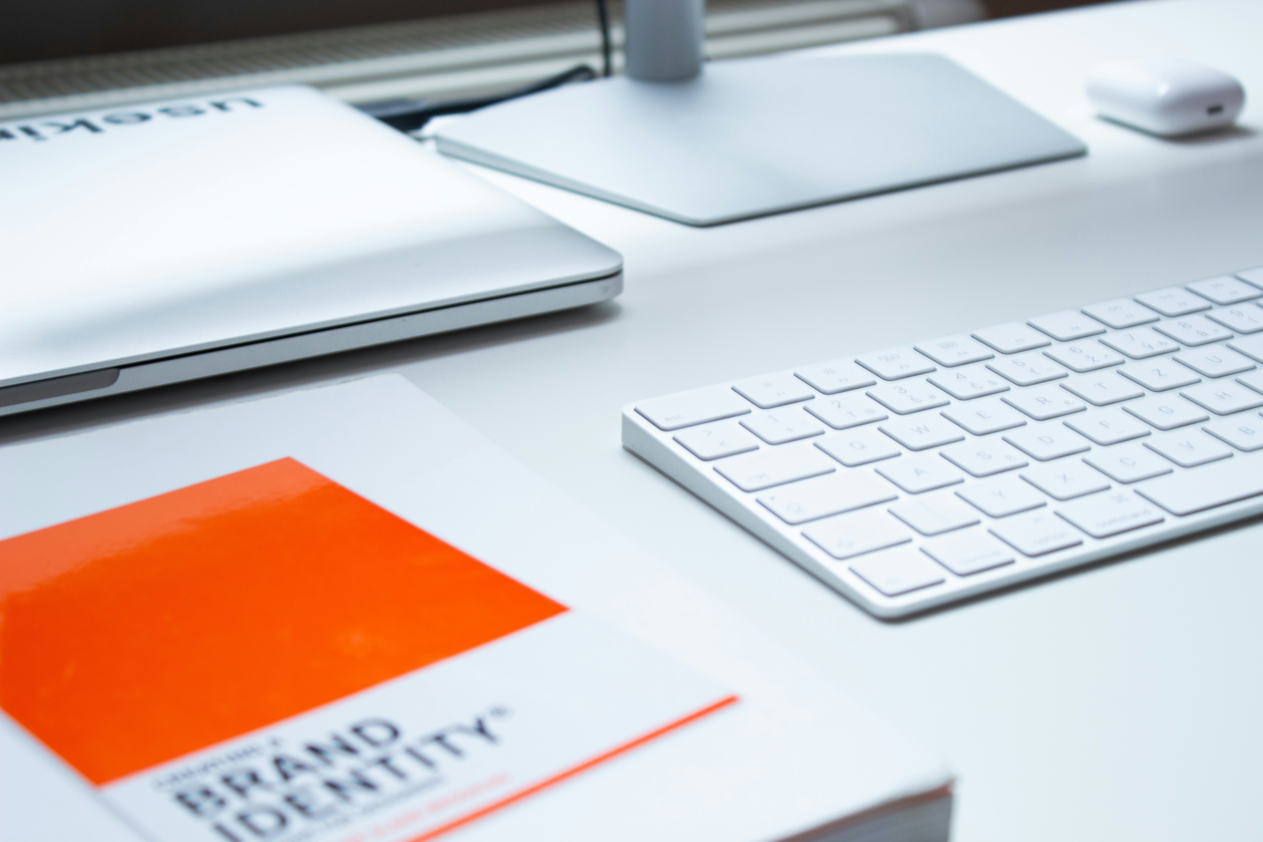 A desk with a laptop and keyword with an orange card that says, “Brand Identity”